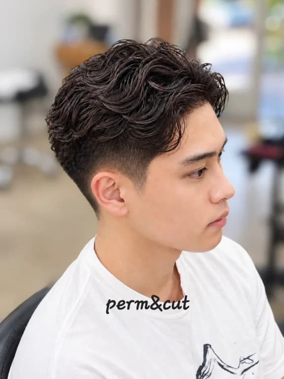 Stylish perm with a textured finish and a clean fade.