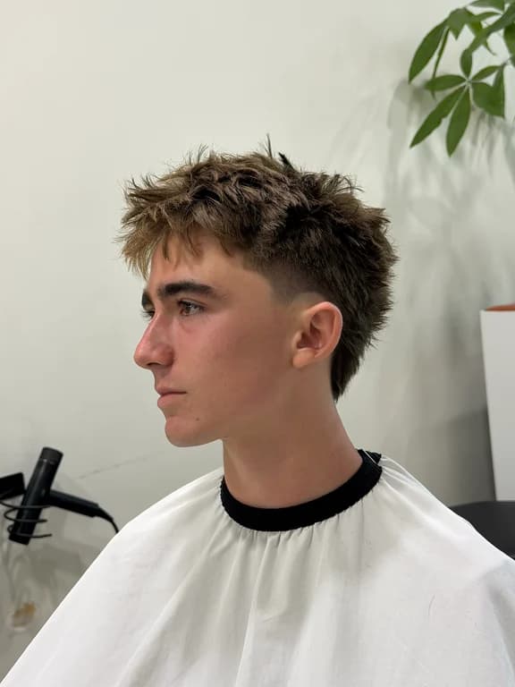 Textured hairstyle with a clean fade and defined shape.